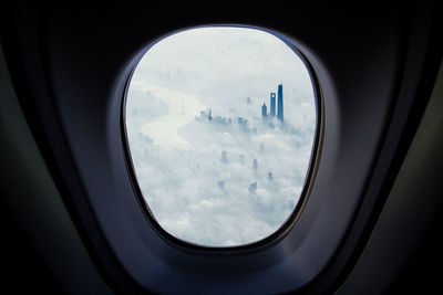 Modern buildings covered with clouds seen through airplane window