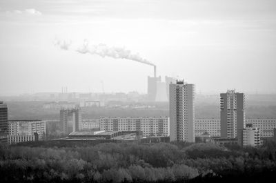 Smoke emitting from factory against sky