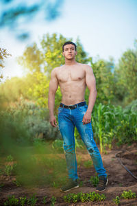 Full length portrait of shirtless man standing on land