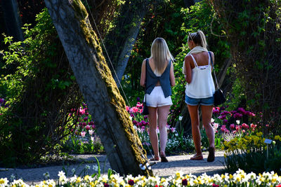 Rear view of women walking on flowering plants