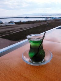 Close-up of water in glass on table against sea