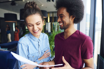 Smiling business couple looking with document in office