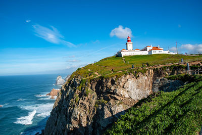 Lighthouse by sea against sky