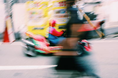 Blurred motion of people riding motorcycle on road