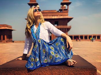 Full length of woman sitting against historic building