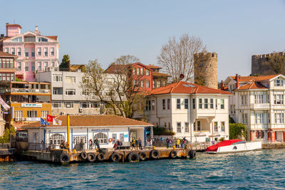 Boats in river by buildings against sky