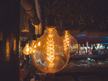 Illuminated light bulbs hanging at night