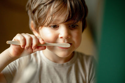 The boy brushes his teeth with a toothbrush made of ecological material