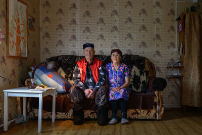 Elderly woman and man sitting on a sofa  in room in village house