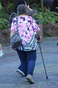 Rear view of woman with umbrella walking on footpath