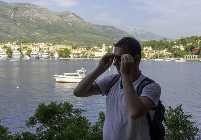 Mature man wearing sunglasses while standing against lake