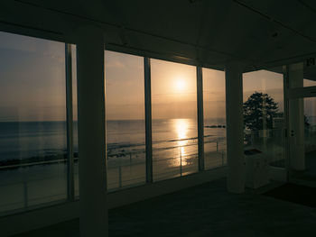 Scenic view of sea seen through glass window at sunset