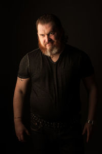 Portrait of mid adult man standing against black background