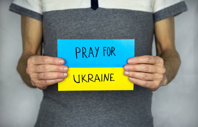 Man with pray for ukraine text on ukrainian flag