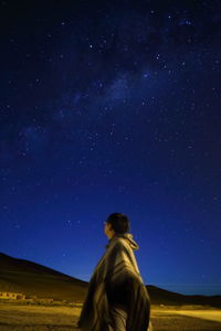 Side view of man standing against star field at night