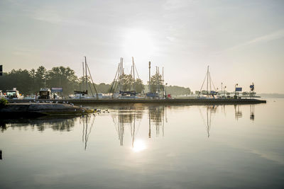 Sailboats moored at harbor against sky