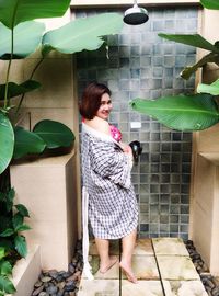 Portrait of smiling woman standing against wall