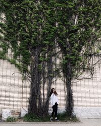 Woman standing by tree against sky