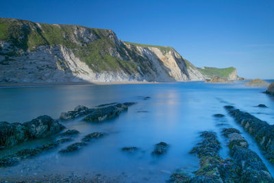 Scenic view of sea and mountains against clear blue sky