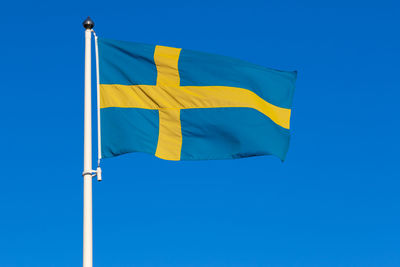 Low angle view of flag against clear blue sky