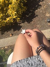 Midsection of woman holding hand by flowering plants