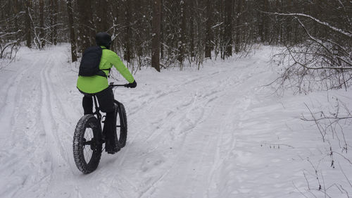Man riding bicycle on snow covered land