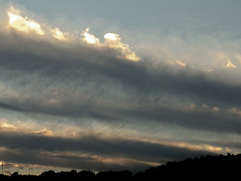 Low angle view of silhouette trees against dramatic sky