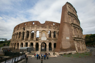 Tourists at historical building against cloudy sky