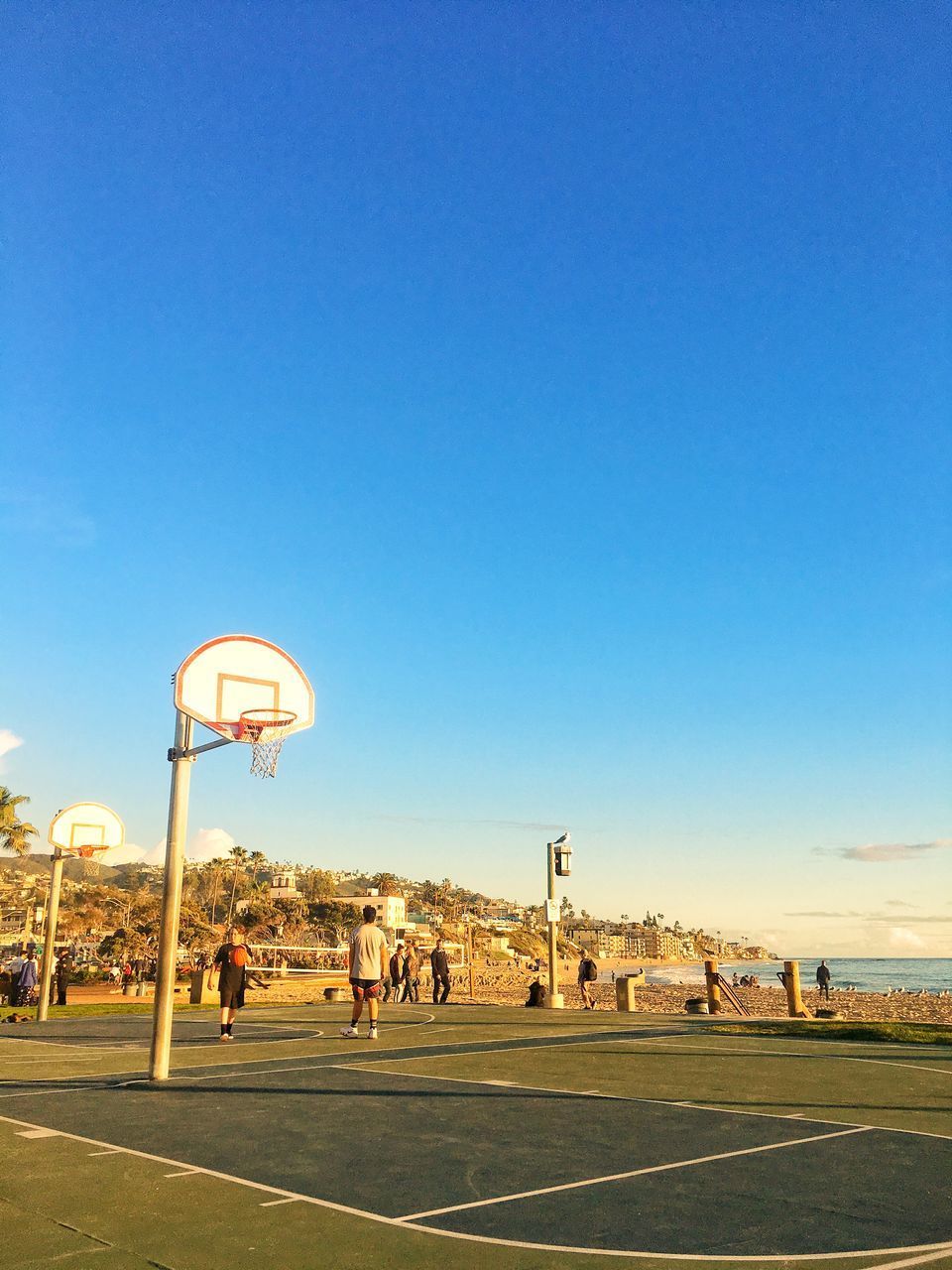 PEOPLE PLAYING BASKETBALL HOOP AGAINST BLUE SKY