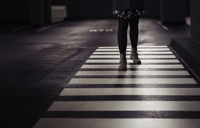 Low section of woman standing on zebra crossing