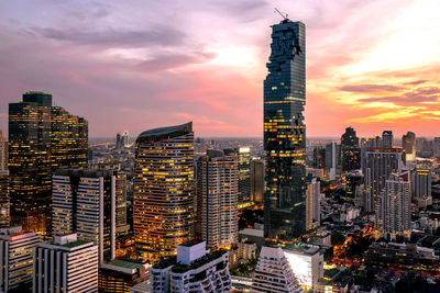 Modern buildings in city against sky during sunset