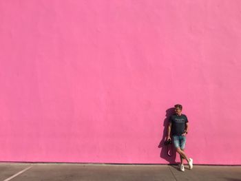 Full length of man walking on pink wall