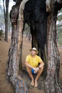 Portrait of man sitting on tree trunk