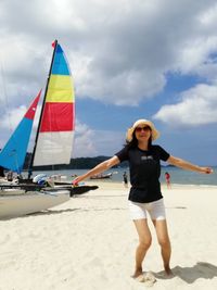 Portrait of cheerful woman with arms outstretched standing at beach