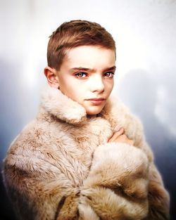 Portrait of boy in fur coat against colored background