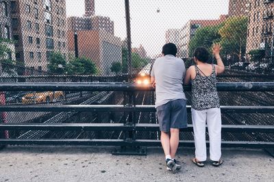 Rear view of friends standing against railing