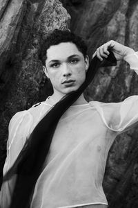 Young male with  androgynous look shot outdoor in black and white with rocks in background.