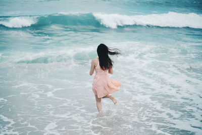 Rear view of woman running in the sea