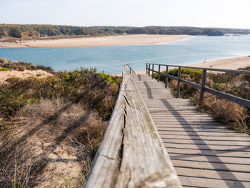 Wooden walkway by sea against sky