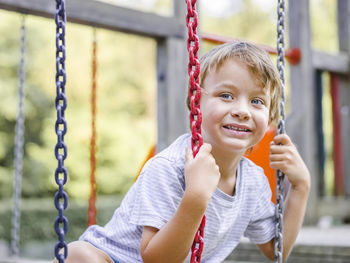 Boy enjoying on swing at playground