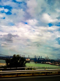 View of bridge over city against cloudy sky