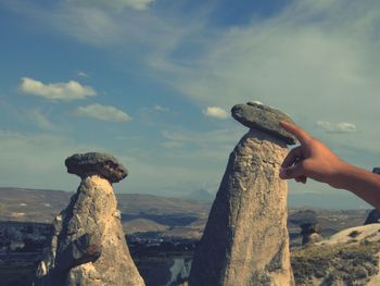 Man holding rock against sky