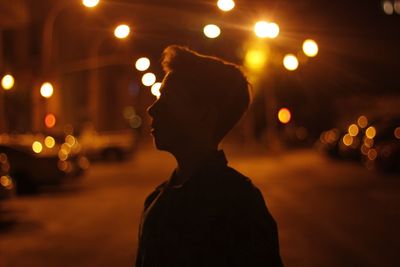 Rear view of woman on illuminated street at night