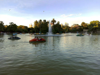 People in boat on river against sky