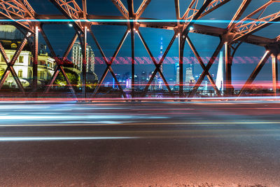 Light trails on bridge against sky in city at night
