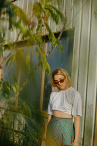 Woman wearing sunglasses standing against plants