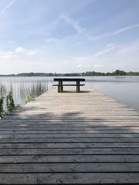 Wooden jetty on pier over lake against sky