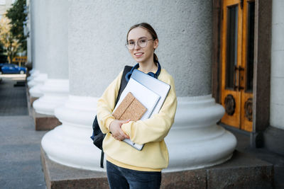 Scholarships for college students. happy college student girl with laptop and books near college