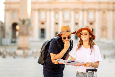 Happy tourists looking at a map and choose a hotel. couple of tourists on vacation in rome, italy. 