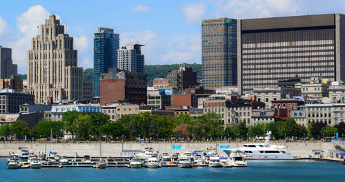 Boats moored at harbor against buildings in city